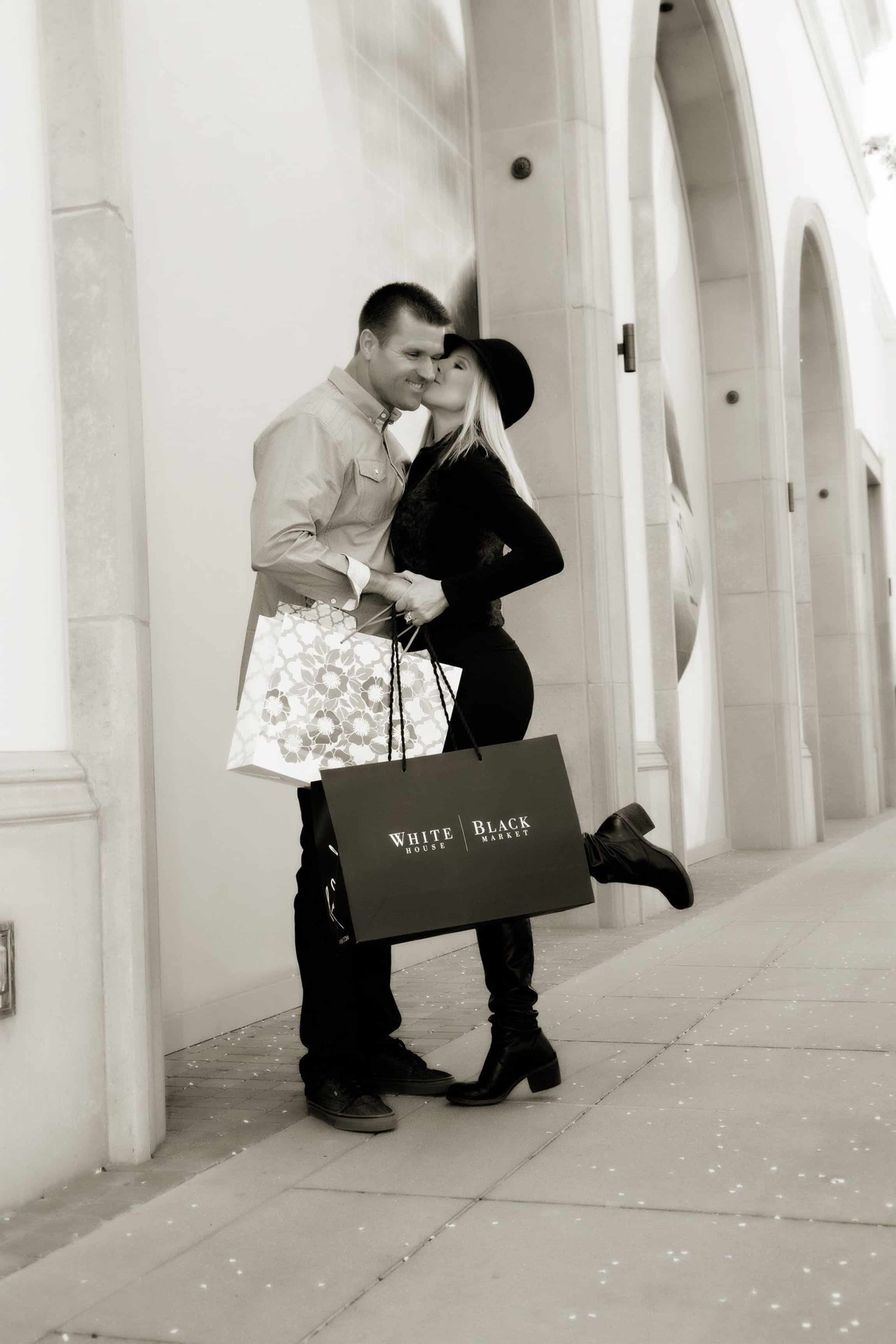 Woman holding a shopping bag kissing a man on the cheek.