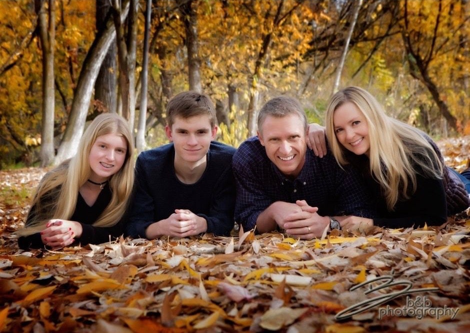 Family posing outside while laying in leaves