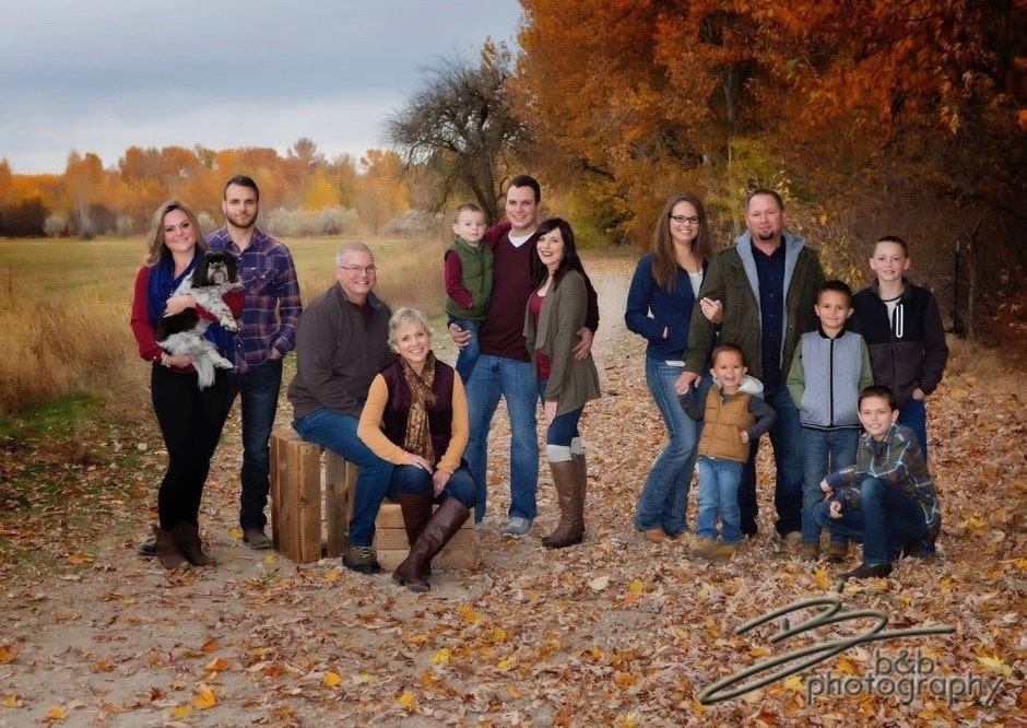 Extended family pictured together with children and a beautiful fall backdrop.