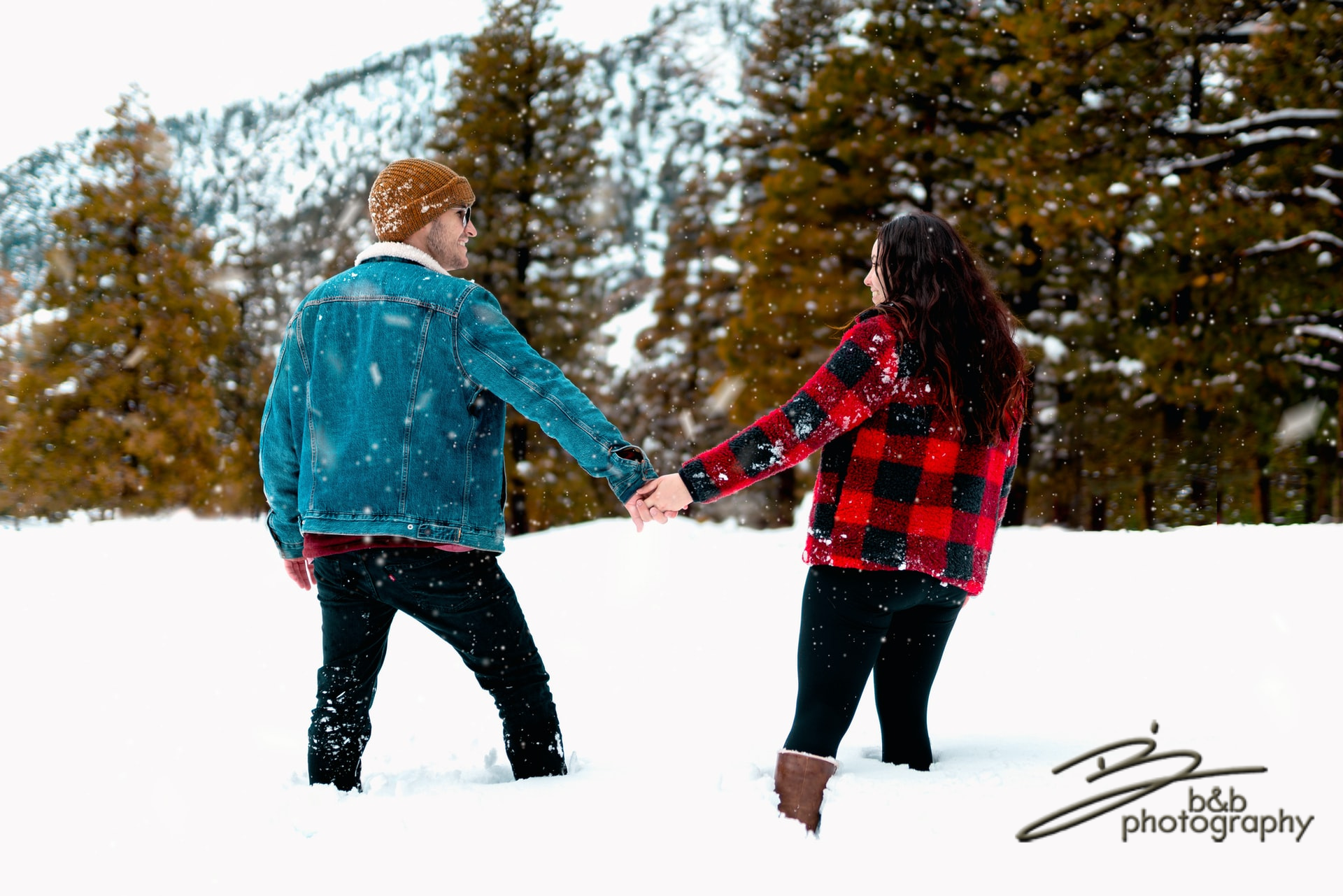 Couple holding hands in the snow looking at each other