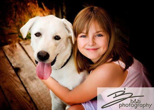 Professional photo of a girl hugging her labrador dog